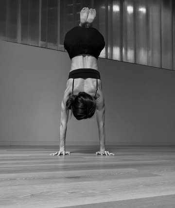 Caitlyne holding a handstand on a studio floor against a paneled wall